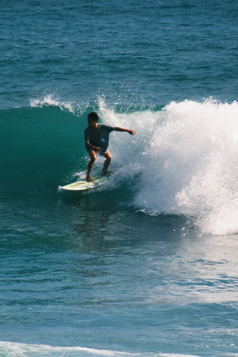A surfer leans into a turn on a green wave during a surf trip.