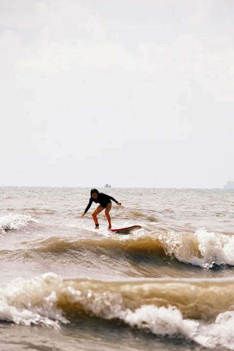 A student practises a low surfing stance on a whitewater wave.